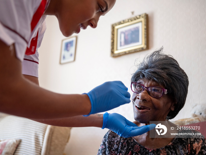 Nurse�taking care of elderly woman, taking nasal sample for testing