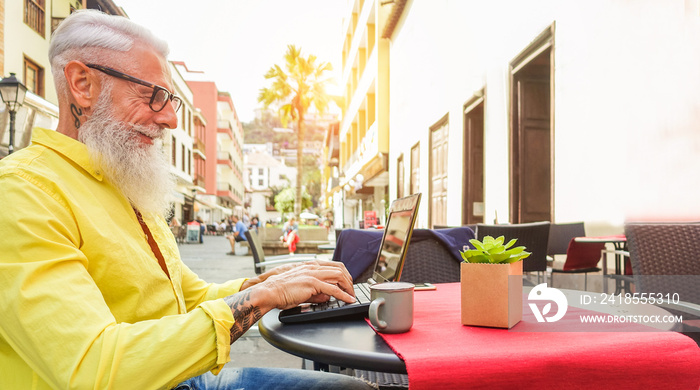 Happy hipster man using laptop in bar cafeteria outdoor - Mature trendy male having fun surfing onli