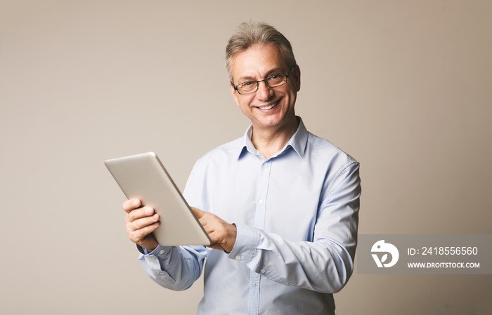 Mature man using digital tablet, studio background