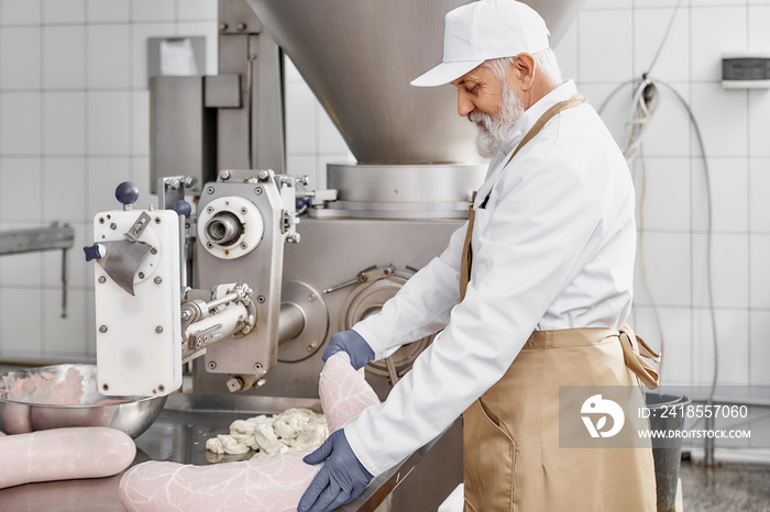 Butcher working with production of sausages at factory.