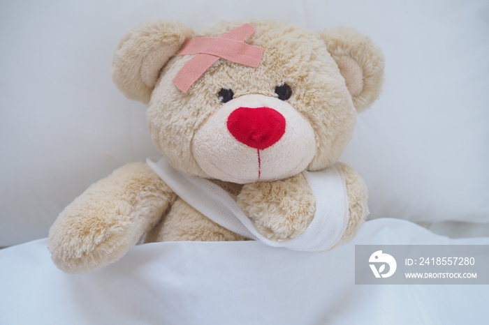 泰迪熊穿着受伤的衣服，手受伤了。躺在床上睡觉。孩子生病了