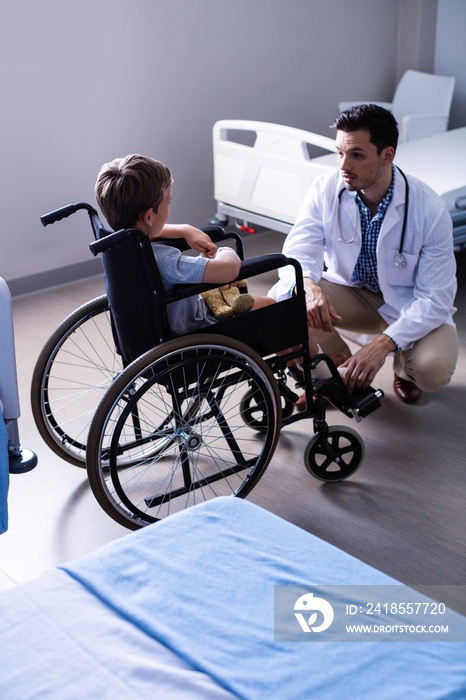 Male doctor interacting with child patient in ward