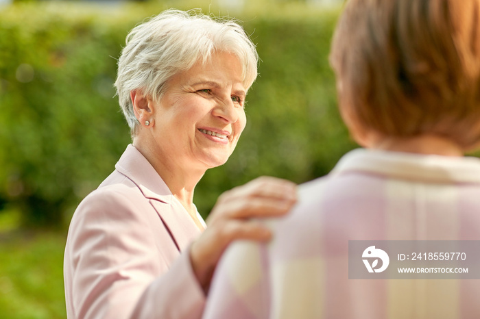 old age, retirement and people concept - two senior women or friends talking at summer park