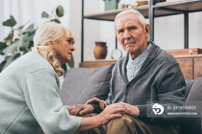 retired wife looking at senior husband in living room