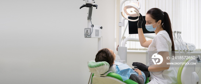 Caucasian woman dentist doctor in office with dental equipment microscope treats teeth to patient in