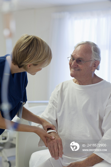 Caring nurse checking on senior patient in hospital room