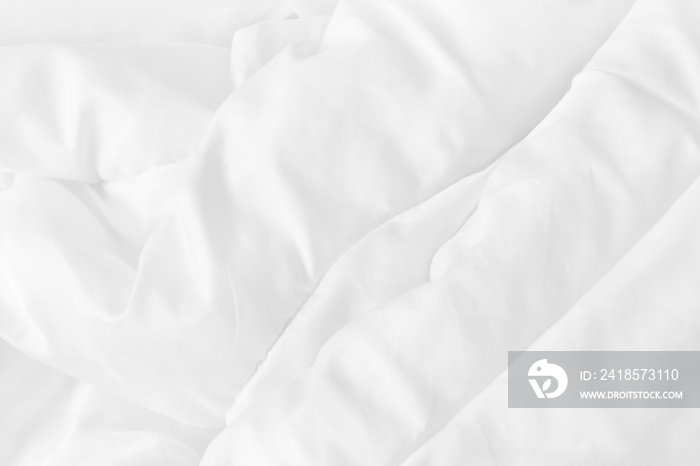 早上醒来后，卧室里白色床单和褶皱凌乱的毯子的特写俯视图
