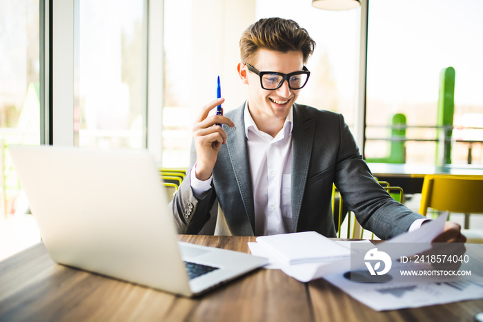 Business man working at office with laptop and documents on his desk. Analyze plans, papers, hands k