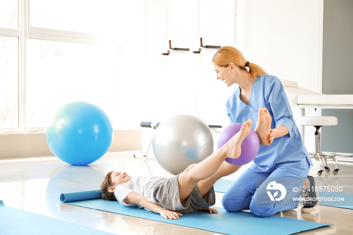 Physiotherapist working with little boy in rehabilitation center