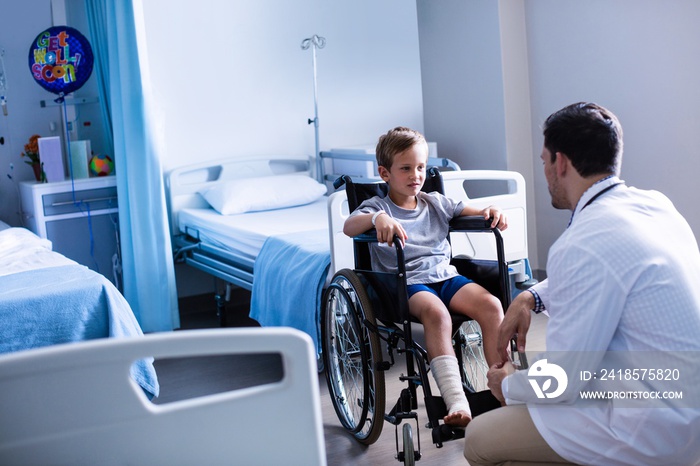 Male doctor interacting with child patient in ward