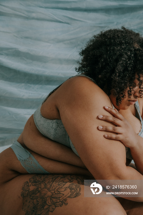 close up portrait of a plus size afro indigenous person hugging self