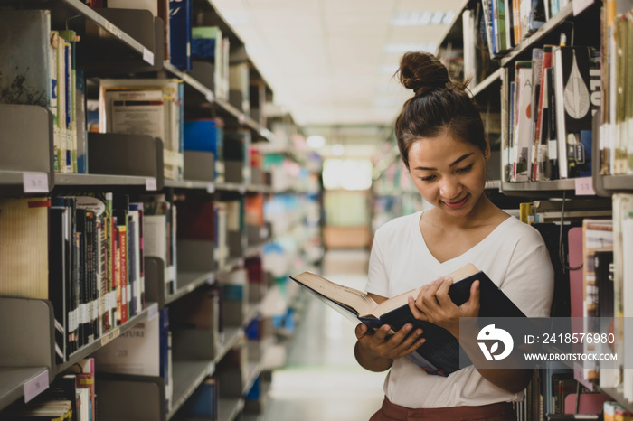 Young Asian women are searching for books and reading books on the tables and aisles of the college 