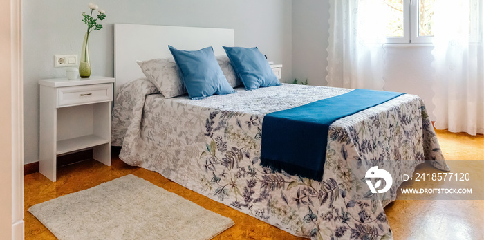 Interior of cozy double bedroom decorated with quilt and curtains