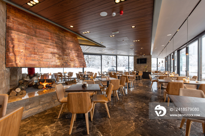 Interior of an empty mountain restaurant with large fireplace in the middle