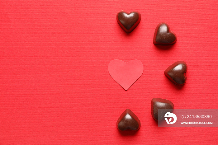 Tasty heart-shaped candies on red background