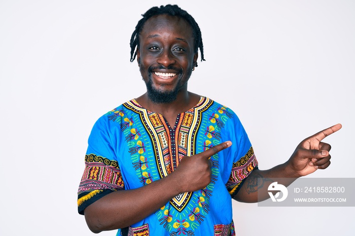 Young african american man with braids wearing traditional africa tshirt smiling and looking at the 