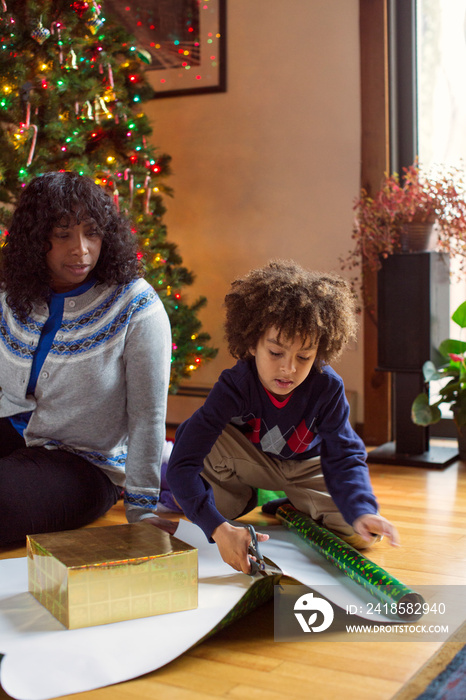 Boy (6-7) helping woman with wrapping christmas presents