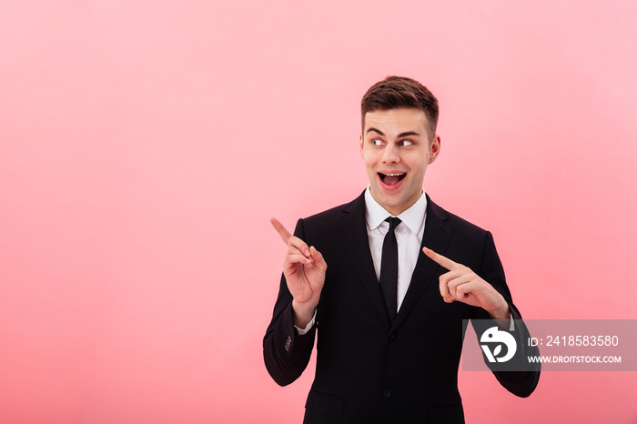 Young businessman pointing at copy space and smiling