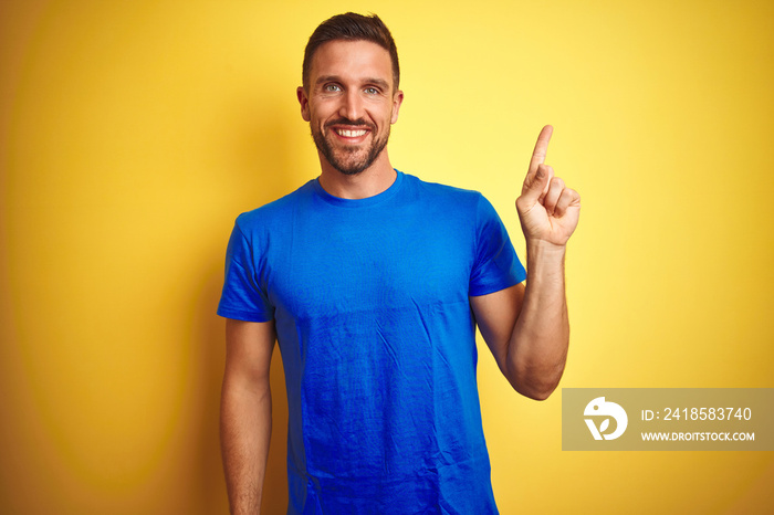 Young handsome man wearing casual blue t-shirt over yellow isolated background with a big smile on f