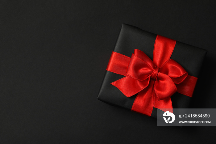 Gift box with red bow on black background