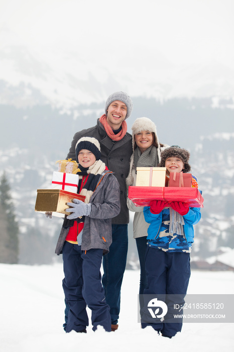 Portrait happy family with Christmas gifts in snowy field