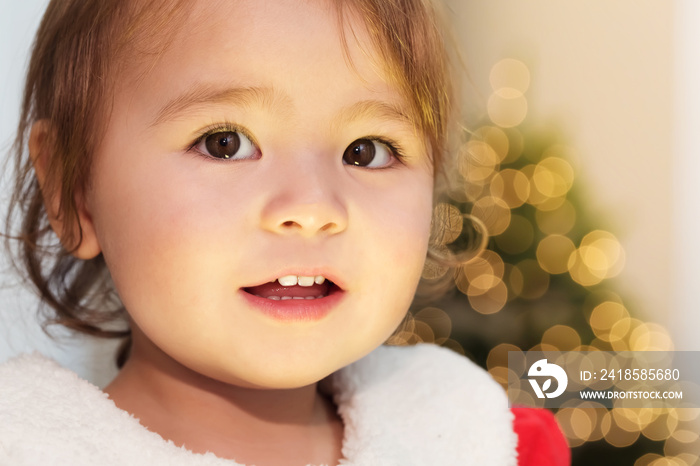 Little girl smiling in front of her Christmas tree