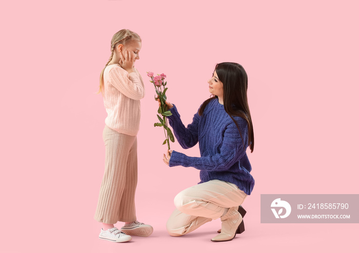 Happy mother greeting her little daughter with tulip flowers on pink background