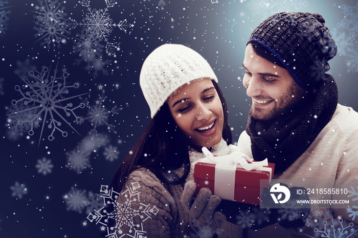 Composite image of winter couple holding gift