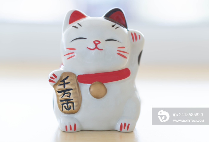 Maneki neko幸运猫在手上展示文本，意思是在桌子上丰富，选择焦点