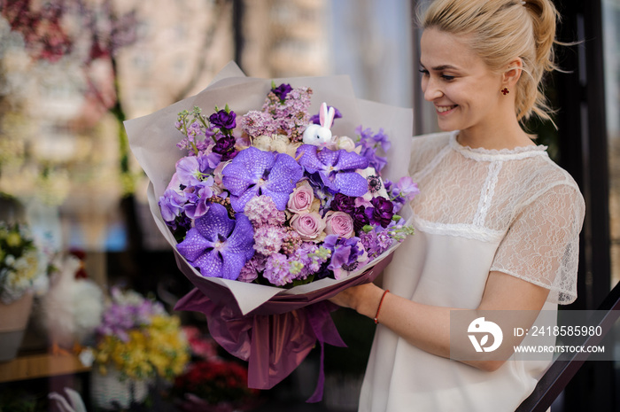 happy woman with beautiful bouquet of purple orchids and lilacs and roses in her hands