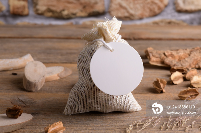 Round white gift tag mockup on gift packet on rustic wooden background with boho decoration. Spring 