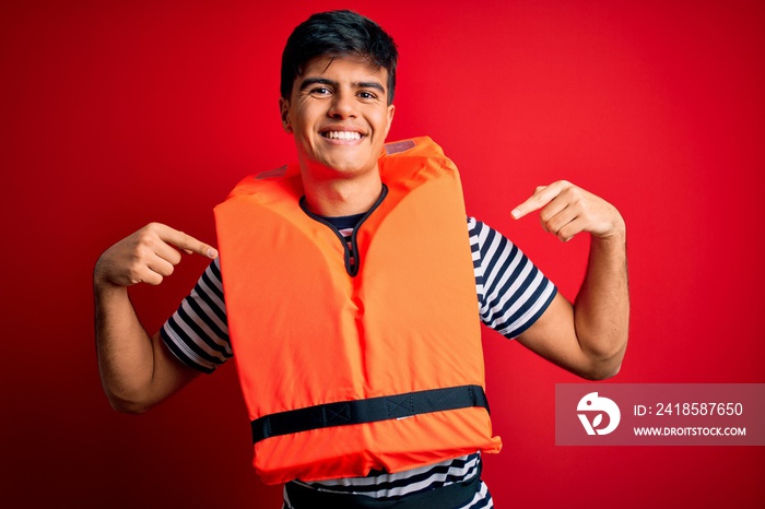 Young handsome man wearing orange safety life jacket over isolated red background looking confident 