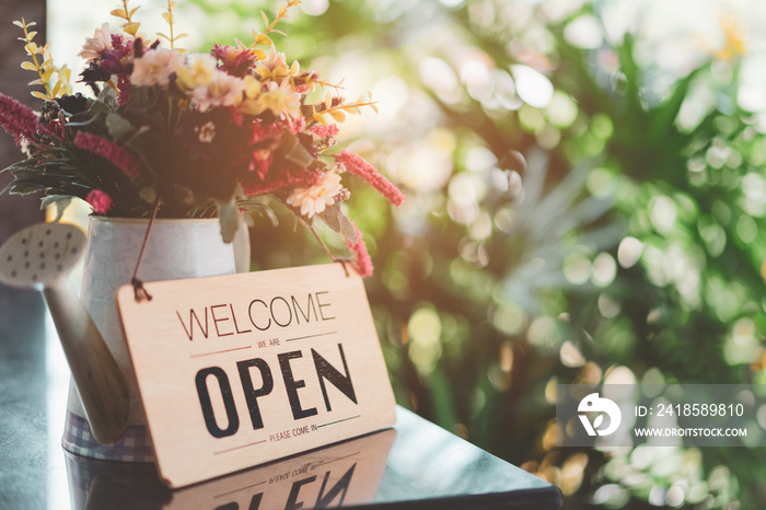 Open sign front of cafe shop with flower and bokeh light abstract background.