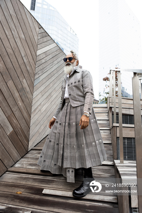 gray hair bearded man wearing skirt suit in modern city location