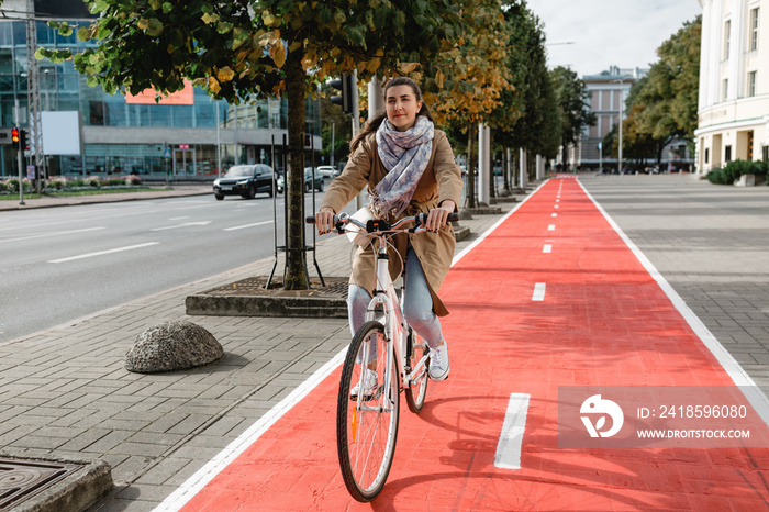 traffic, city transport and people concept - woman riding bicycle along red bike lane or two way roa