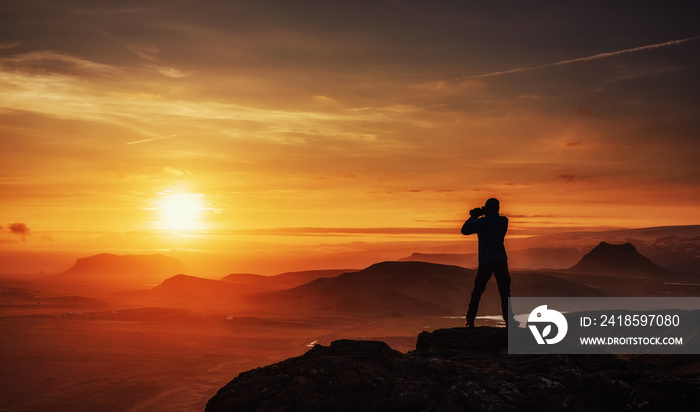 Happy man standing on a cliff at sunset.