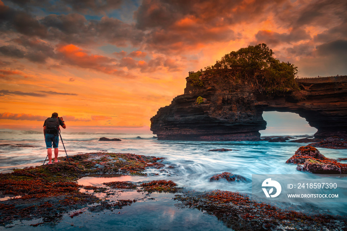 Photography take photo of Tanah Lot Temple on sea at sunset in Bali Island, Indonesia.