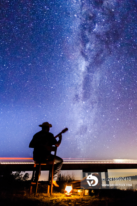 Musician playing under the Milky Way