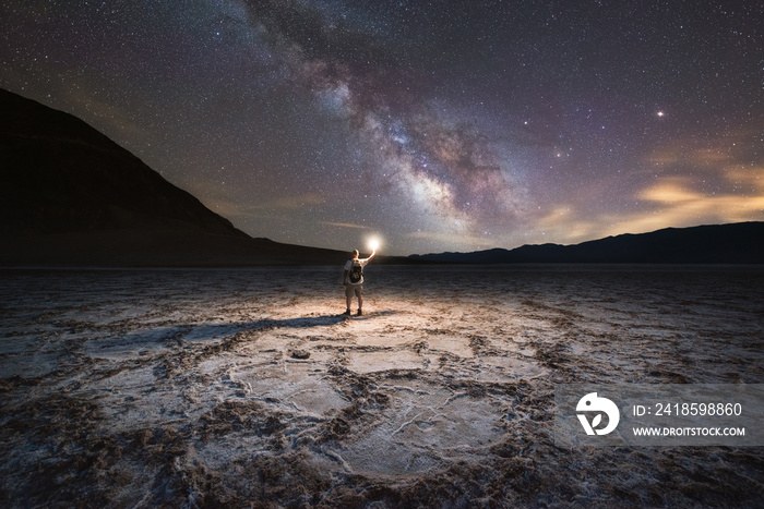 Man light painting Badwater Basin under the Milky Way Galaxy