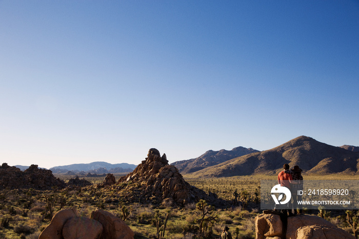 Desert landscape with young couple standing on rock