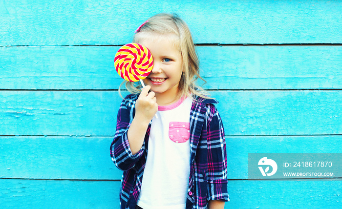 快乐的微笑的孩子与甜蜜的棒棒糖玩得五彩缤纷
