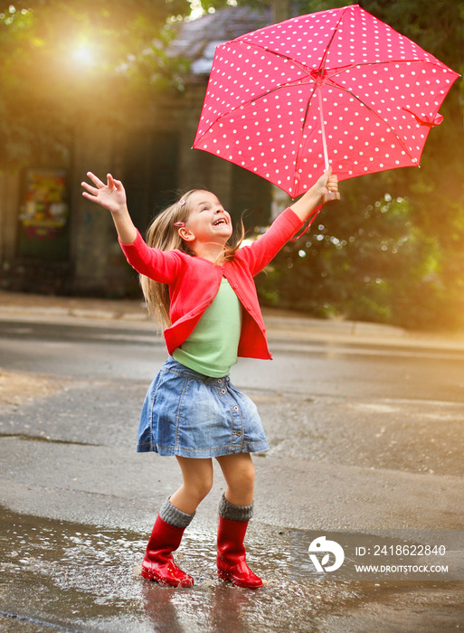 孩子打着圆点伞，穿着红色雨靴