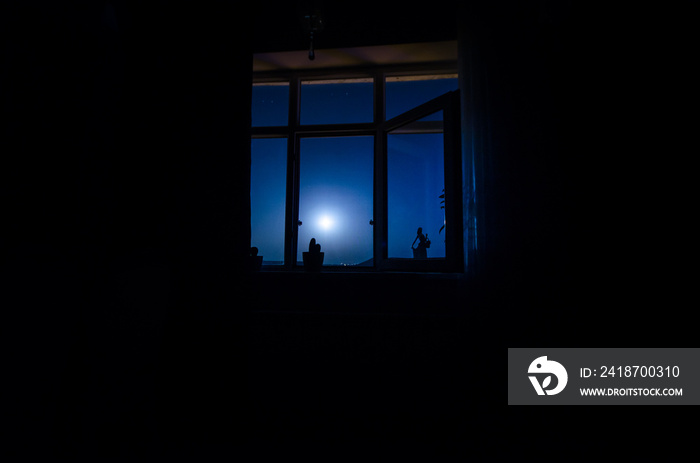 Night scene of moon seen through the window from dark room.