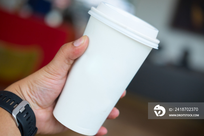 mans hand holding white empty paper coffee cup