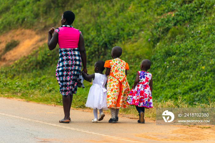 一个乌干达妇女带着三个孩子走在街上