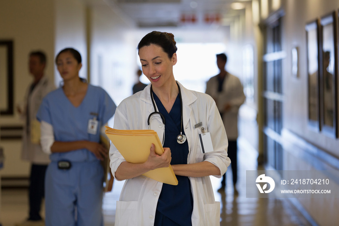 Female doctor making rounds in hospital corridor