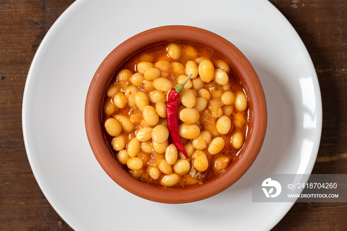 Hot turkish bean stew on wooden background. Ispir beans cooked in a casserole - Kuru Fasulye. Top vi