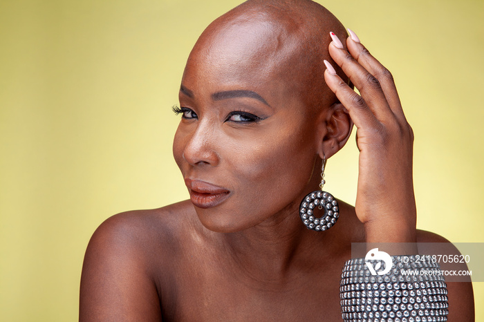 Portrait of woman wearing earrings and bracelets against yellow background