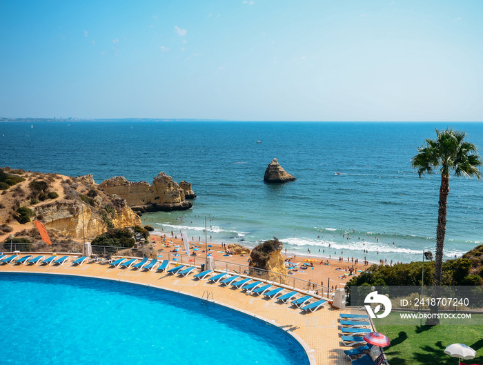 Empty swimming pool overlooking Cova Redonda Beach in Algarve, Portugal during the summer - paradise