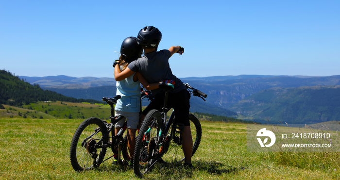 mountain biker, two children with bike and look at the beautiful scenery